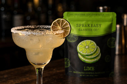 Dried lime wheel on a cocktail glass rim, Speakeasy Garnishes lime pouch in background