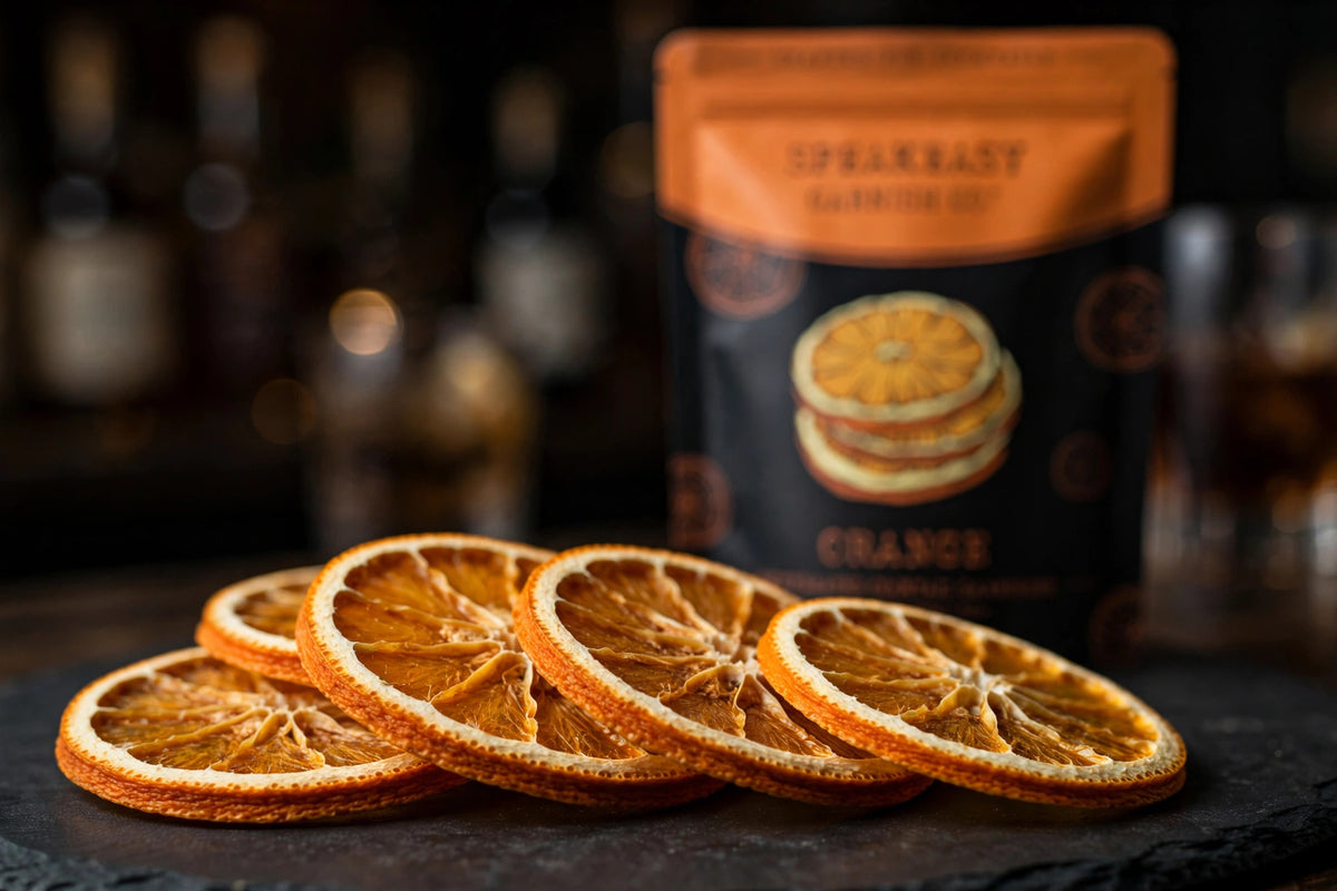 Dried orange wheels fanned on dark slate with Speakeasy Garnishes pouch behind
